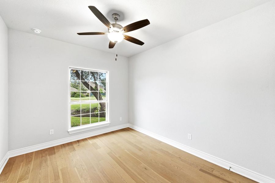 Bright room featuring wood-finish flooring, white baseboards, and a ceiling fan with integrated lighting