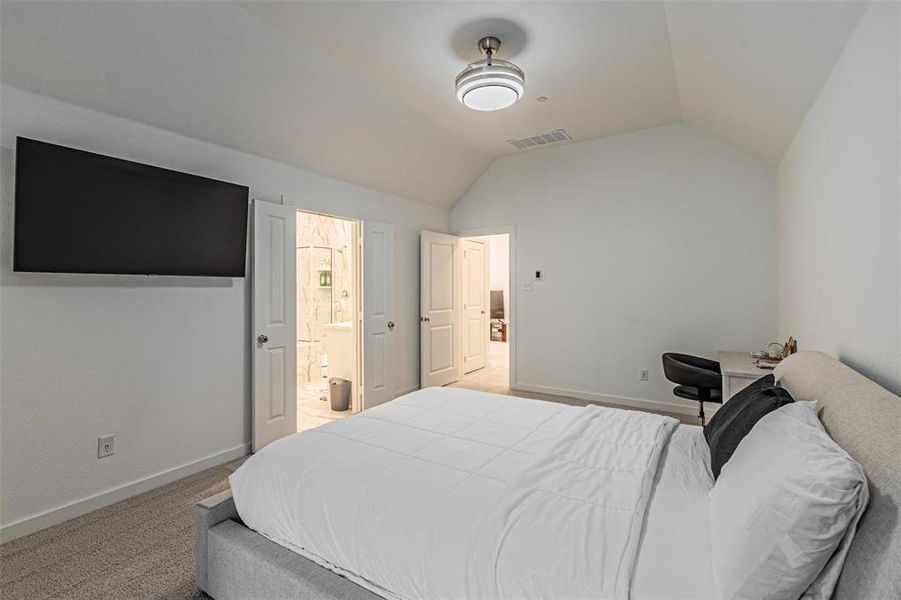Carpeted bedroom featuring lofted ceiling and ensuite bathroom