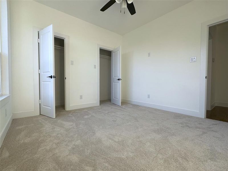 Unfurnished bedroom featuring two closets, light colored carpet, and ceiling fan