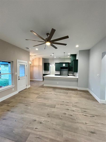 Unfurnished living room with light hardwood / wood-style floors and ceiling fan