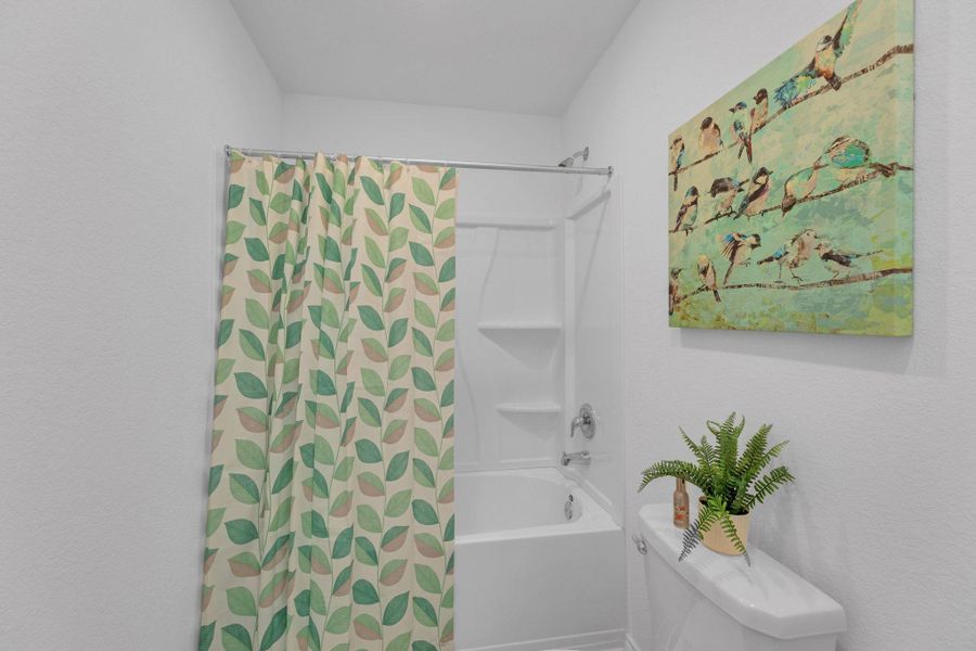 Bathroom featuring toilet and shower / bath combo with shower curtain