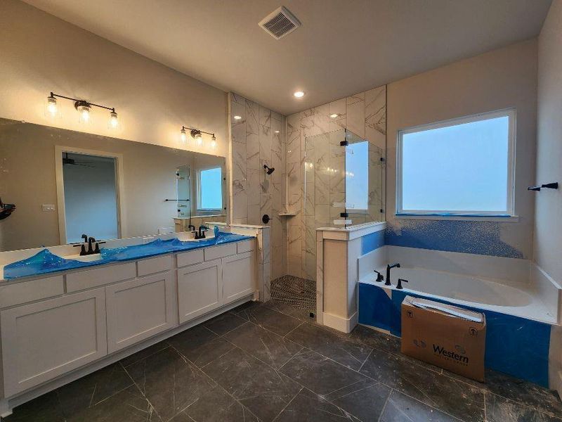 Full bath featuring double vanity, a marble finish shower, and a garden tub