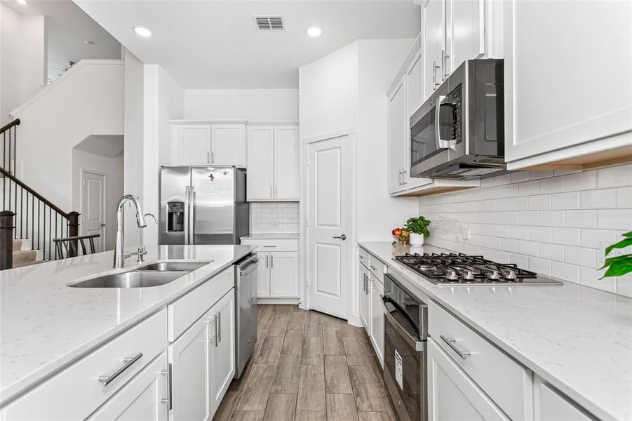 Modern kitchen featuring light cabinetry, stainless steel appliances, and wood-finish flooring