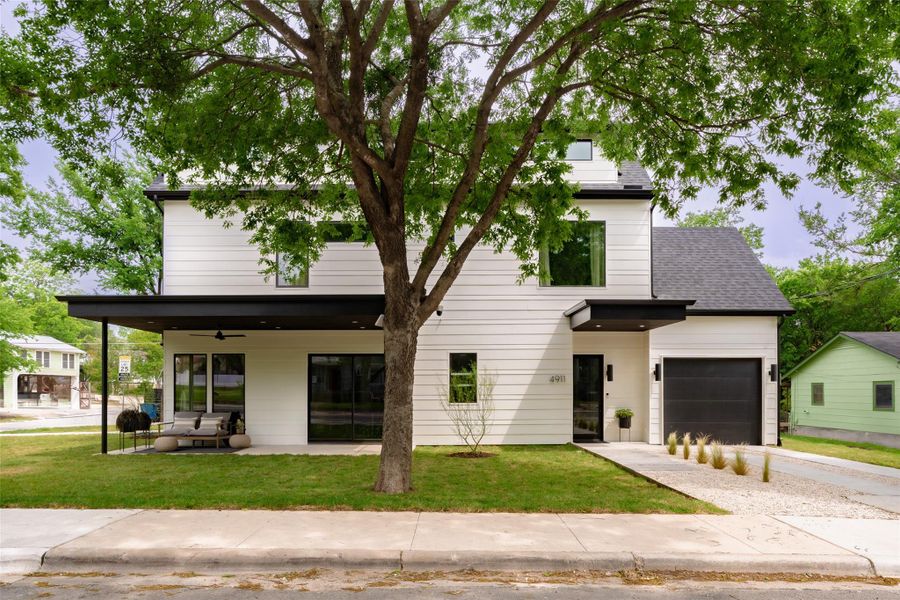 View of front facade featuring a garage, ceiling fan, concrete driveway, and a front lawn