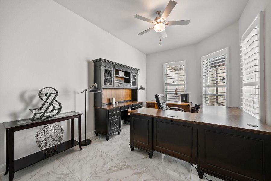 Office with light marble finish floors and a ceiling fan
