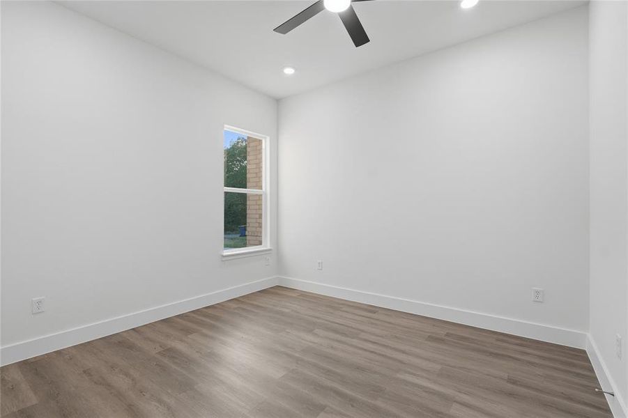 Spacious room featuring wood-finish flooring, a contemporary ceiling fan, recessed lighting, and a double-hung window