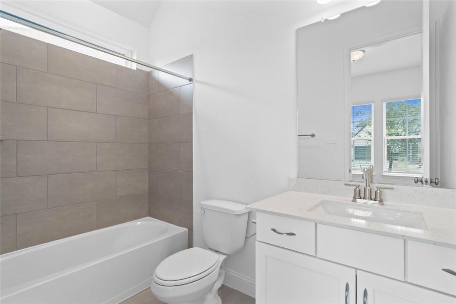 This ensuite secondary bathroom features a modern vanity, tub/shower combination with tile surround, and neutral finishes. This ensuite secondary bathroom features a modern vanity, tub/shower combination with tile surround, and neutral finishes.