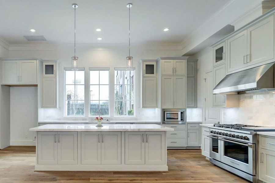 Sunlit kitchen with an expansive, uninterrupted island, designed for both function and flow, reflects the refined aesthetic of this prior build.