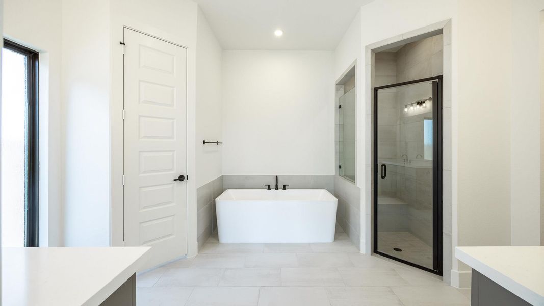 Full bathroom with vanity, a freestanding tub, a stall shower, light tile patterned flooring, and recessed lighting Full bathroom with vanity, a freestanding tub, a stall shower, light tile patterned flooring, and recessed lighting