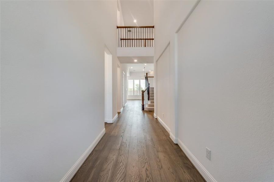 Corridor with a towering ceiling and dark hardwood / wood-style flooring