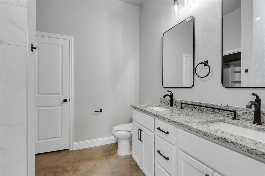 Full bathroom featuring double vanity and concrete flooring