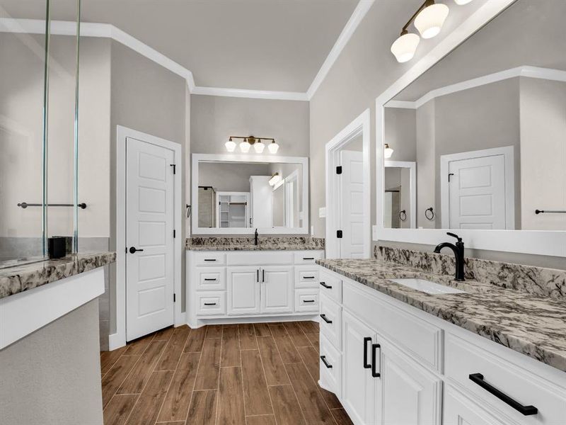 Full bathroom with two vanities, wood tiled floors, and crown molding