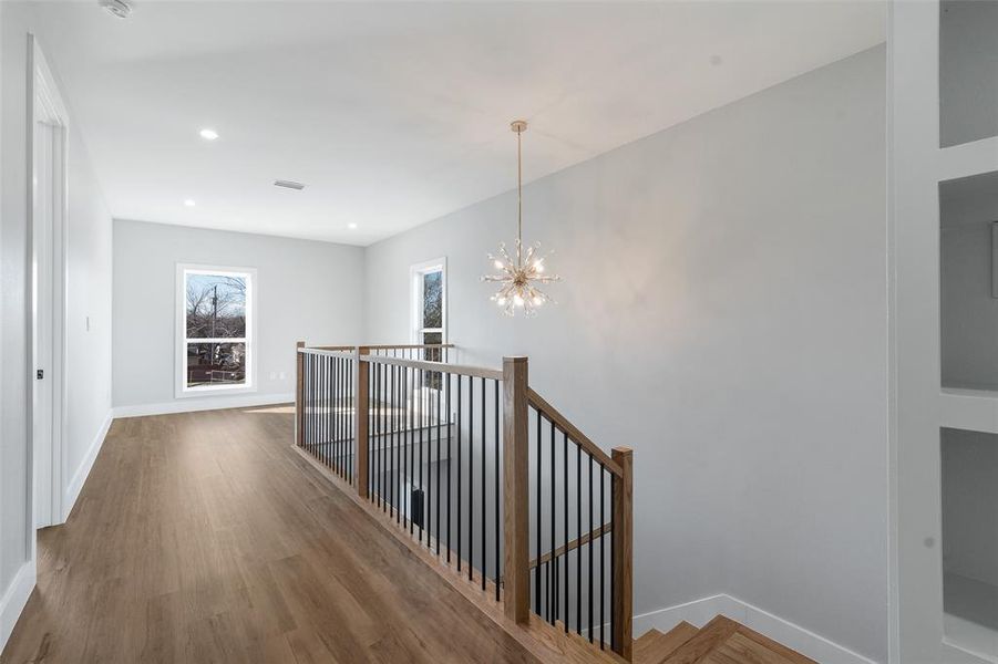 Corridor with an inviting chandelier and hardwood / wood-style flooring