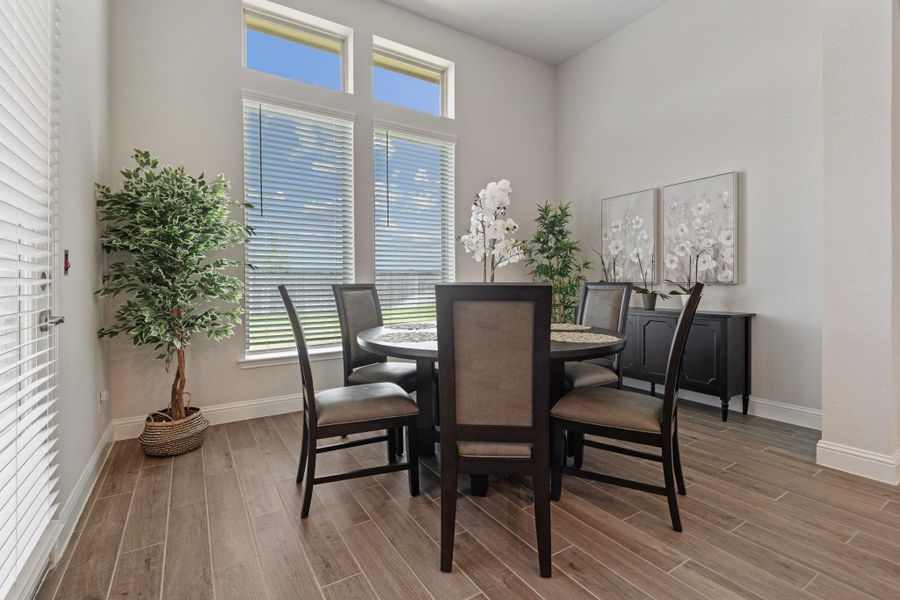 Bright dining area featuring large windows, modern wood-look tile flooring, and tasteful decor with a round table and seating for six. Perfect for intimate gatherings and group activities. Bright dining area featuring large windows, modern wood-look tile flooring, and tasteful decor with a round table and seating for six. Perfect for intimate gatherings and group activities.