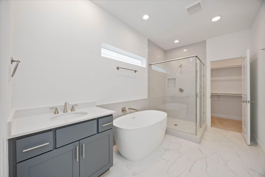 A spa day—every day. This luxe en-suite bath features a freestanding soaking tub, oversized shower with glass enclosure, and easy access to one of two walk-in closets. (Mirrors to be installed prior to close.)