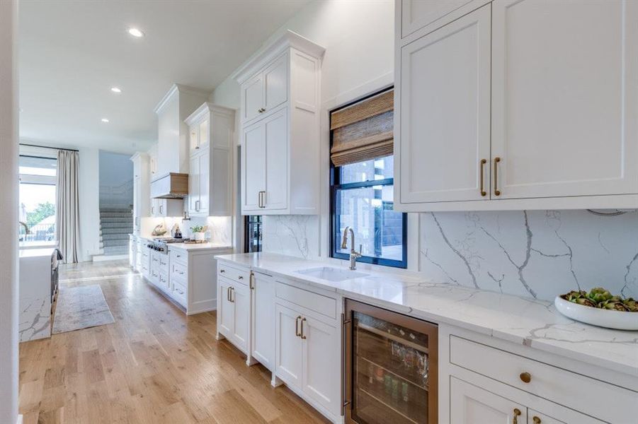 Kitchen with beverage cooler, decorative backsplash, white cabinets, plenty of natural light, and recessed lighting Kitchen with beverage cooler, decorative backsplash, white cabinets, plenty of natural light, and recessed lighting