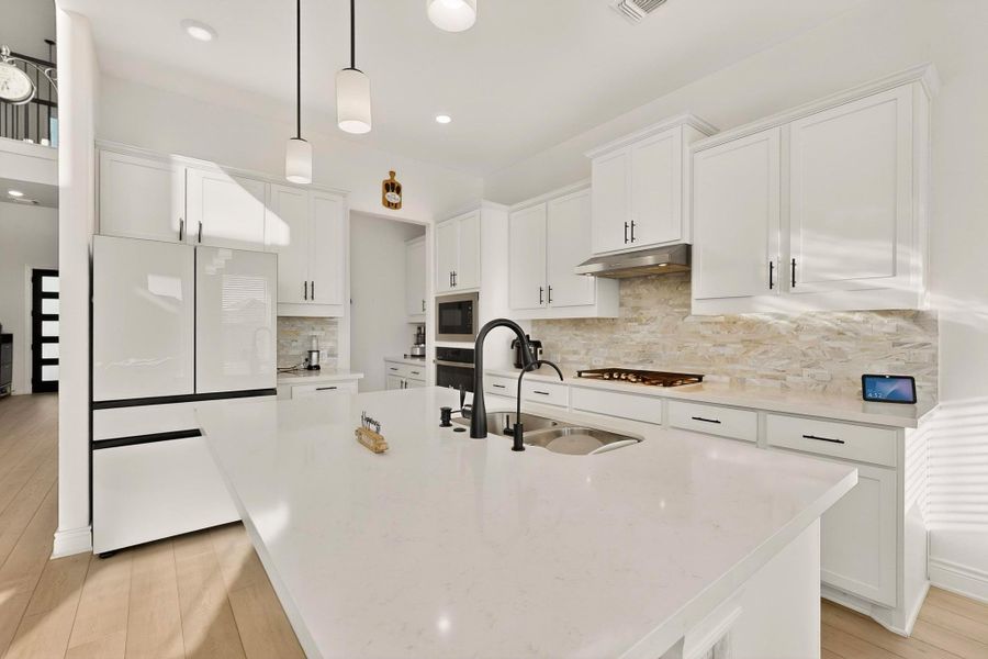 Kitchen with freestanding refrigerator, light wood-style flooring, white cabinets, tasteful backsplash, and recessed lighting