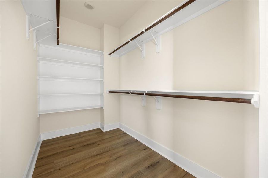 Spacious primary walk-in closet offering plenty of room for organization, with ample hanging space and built-in shelving for all your storage needs