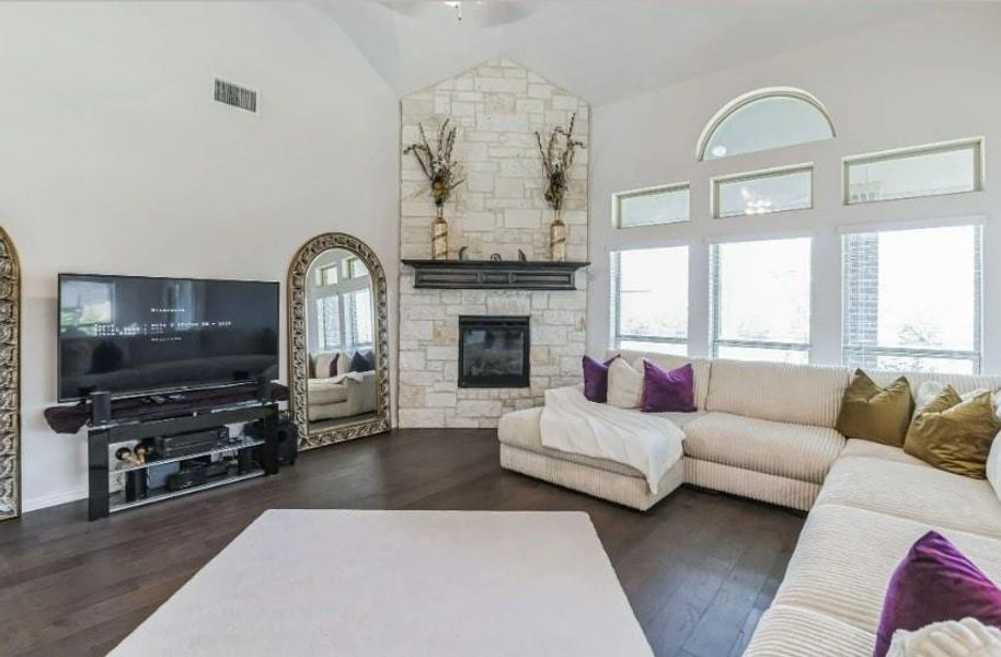 Living room featuring a stone fireplace, high vaulted ceiling, and dark hardwood / wood-style flooring