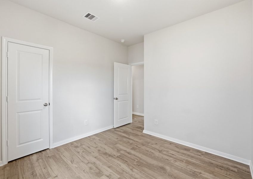 Primary bedroom featuring wood-look flooring and multiple doors.