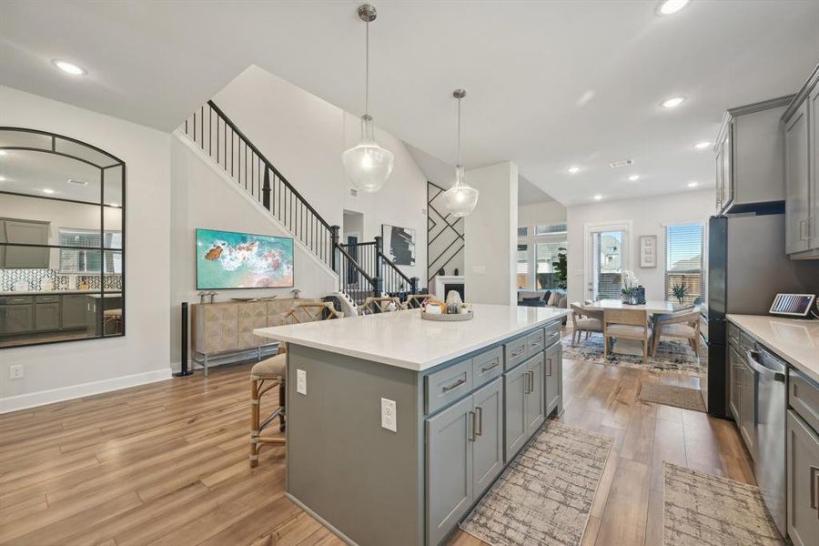 Kitchen with pendant lighting, gray cabinets, light hardwood / wood-style flooring, and a kitchen island