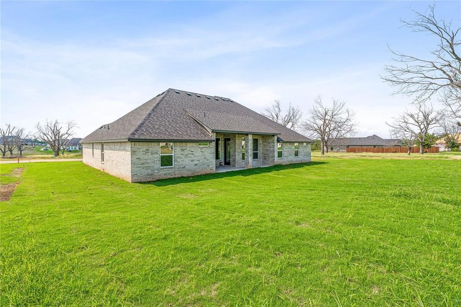 Rear view of house with roof with shingles, a lawn, a patio, and brick siding Rear view of house with roof with shingles, a lawn, a patio, and brick siding