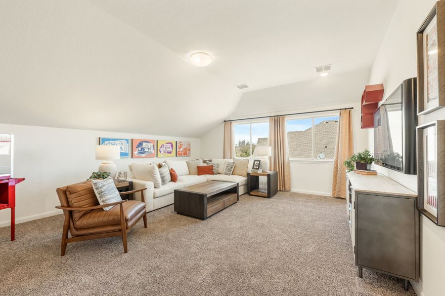 Upstairs bonus room with vaulted ceiling, carpet flooring, sectional sofa, and wall-mounted TV