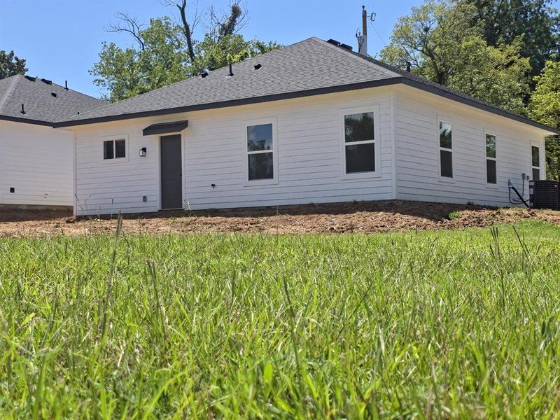 Rear view of property featuring a shingled roof and a lawn Rear view of property featuring a shingled roof and a lawn