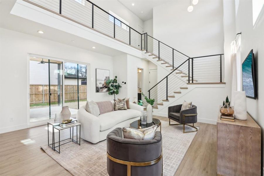 Living room with light hardwood / wood-style flooring and a high ceiling