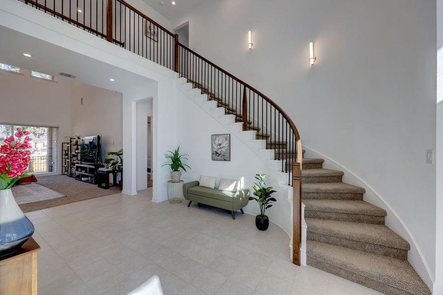Staircase with a towering ceiling and recessed lighting