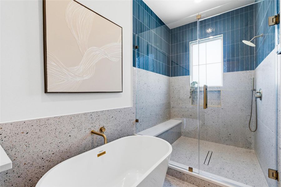 The shower area features a high-contrast combination of terrazzo-style stone and deep blue vertical tiling. Brushed gold hardware and a wall-mounted faucet elevate the sleek, contemporary aesthetic.