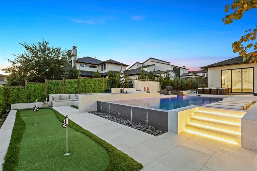 Pool at dusk with area for grilling, a patio, an area to practice putting, and a fenced backyard Pool at dusk with area for grilling, a patio, an area to practice putting, and a fenced backyard