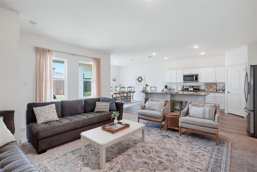 Open-concept living area featuring a kitchen with white cabinetry and stainless steel appliances