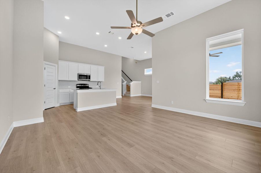 Unfurnished living room with ceiling fan, light wood-style floors, stairs, and recessed lighting