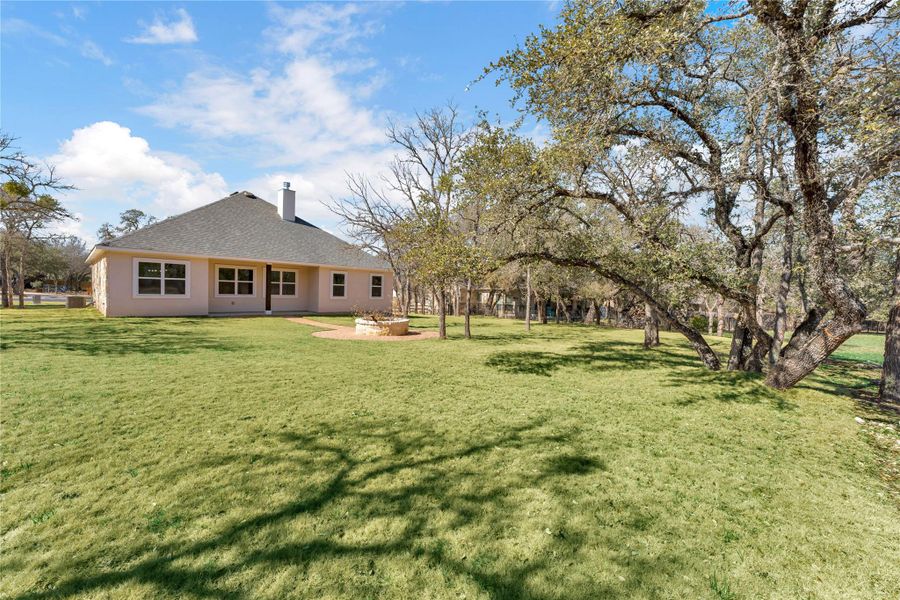 Rear view of house with a patio area, a lawn, a chimney, and roof with shingles