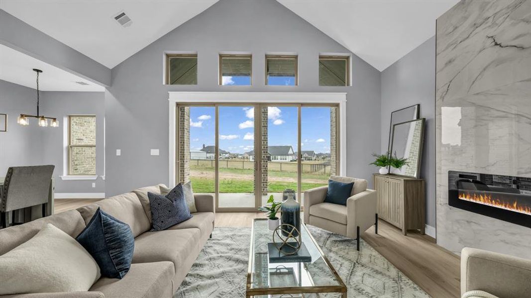 Living room featuring healthy amount of natural light, high vaulted ceiling, wood finished floors, and a premium fireplace