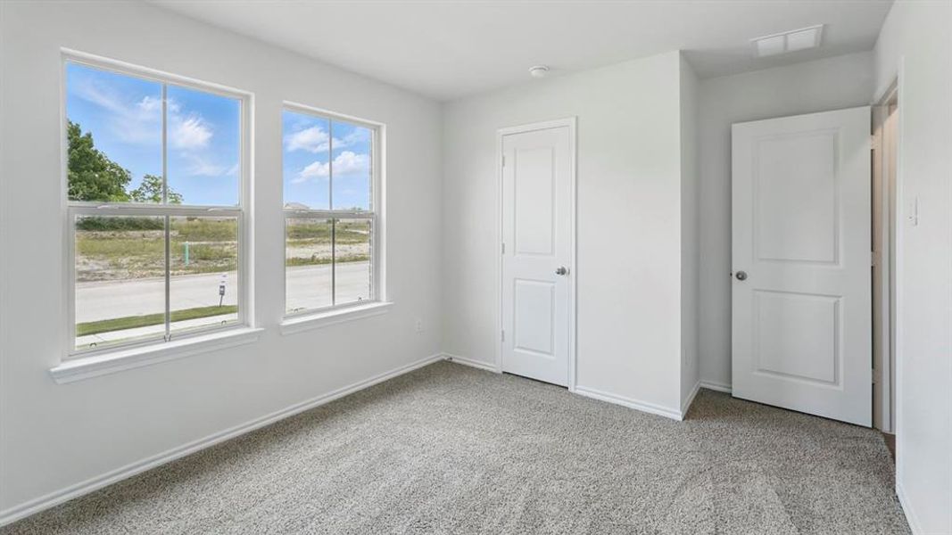 Carpeted room with white walls, two double-hung windows, and two white panel doors
