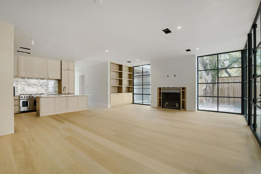 Blonde wood flooring unifies the open-concept living space with a contemporary kitchen and a modern fireplace.