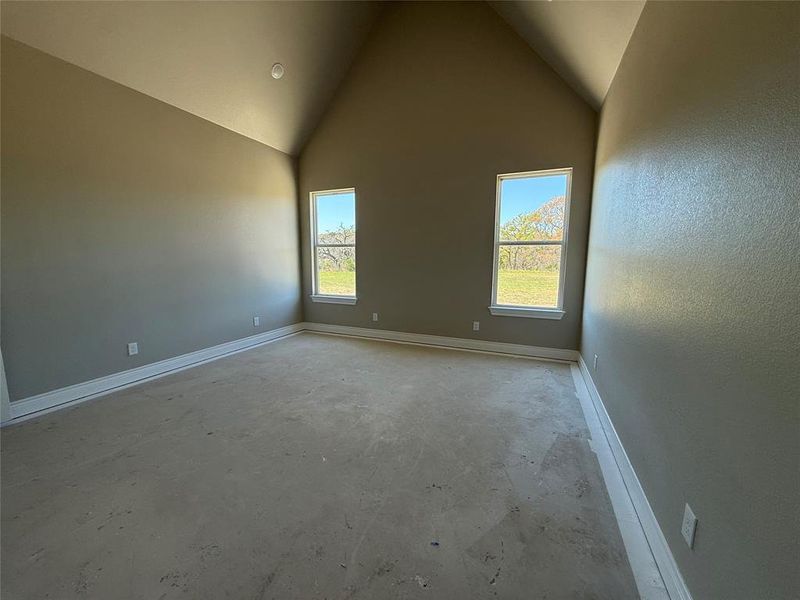 Spare room featuring concrete flooring, healthy amount of natural light, and a high ceiling