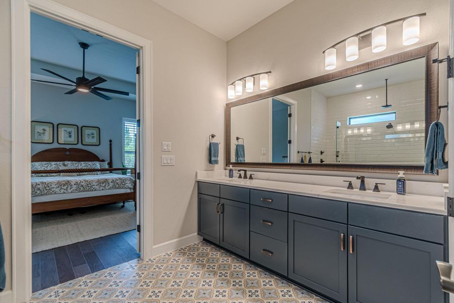 Full bath with double vanity, ceiling fan, a tile shower, connected bathroom, and plenty of natural light