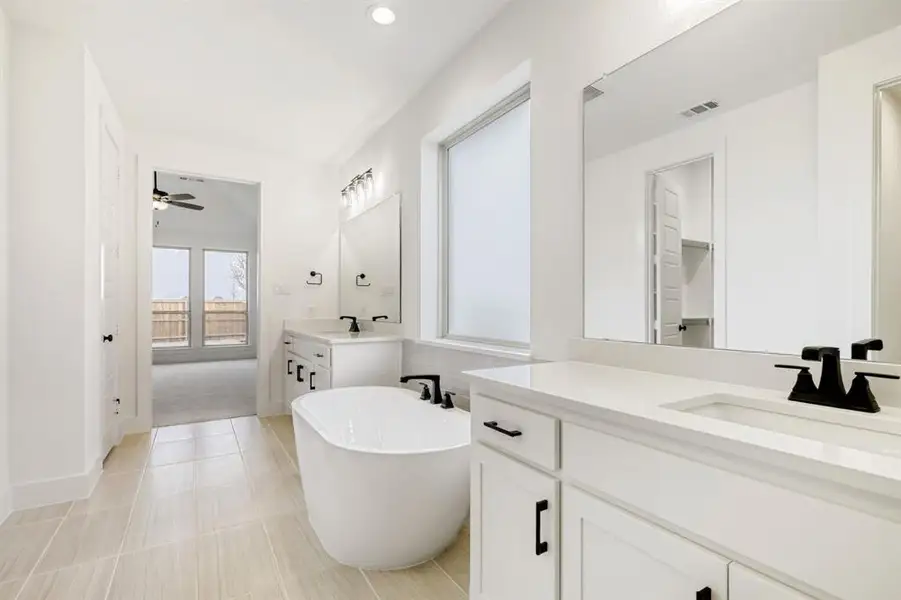 Full bath with a freestanding bath, two vanities, a ceiling fan, and recessed lighting