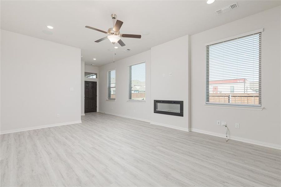 Unfurnished living room featuring light wood-type flooring and ceiling fan