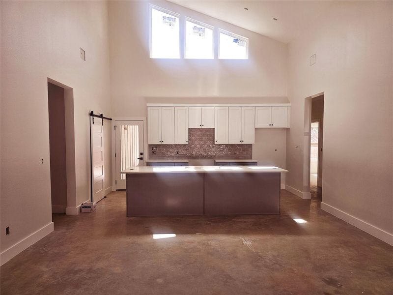 Kitchen with white cabinetry, baseboards, backsplash, and a center island