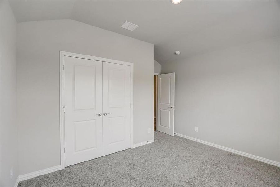 Unfurnished bedroom with light carpet, lofted ceiling, and a closet