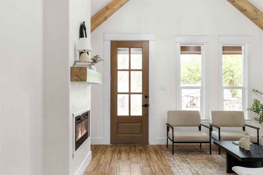 Doorway featuring high vaulted ceiling, beamed ceiling, and wood-type flooring