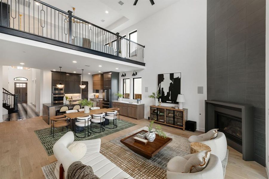 Living area with plenty of natural light, recessed lighting, light wood-style floors, a fireplace, and a high ceiling Living area with plenty of natural light, recessed lighting, light wood-style floors, a fireplace, and a high ceiling