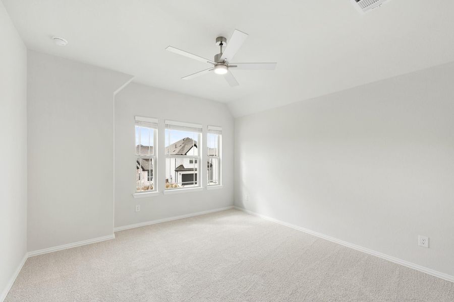 Empty bedroom with vaulted ceiling, ceiling fan, carpet flooring, and triple windows