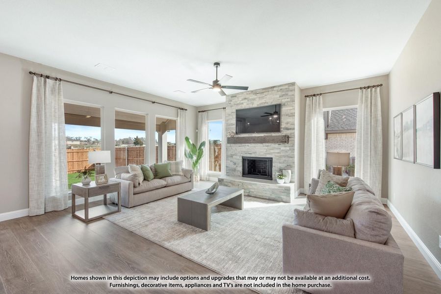 Living room with stone fireplace, ceiling fan, hardwood floors, and large windows with backyard views Living room with stone fireplace, ceiling fan, hardwood floors, and large windows with backyard views