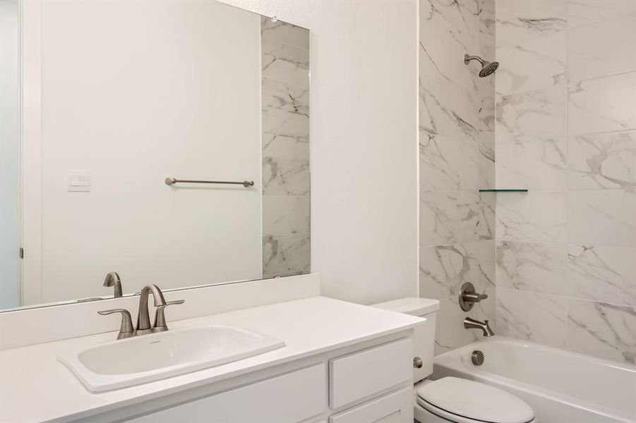 Full bathroom featuring tiled shower / bath combo, toilet, and vanity