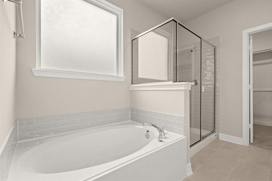 This additional view of your primary bathroom features tile flooring, fresh paint, walk-in shower, a separate garden tub, and a large walk-in closet.